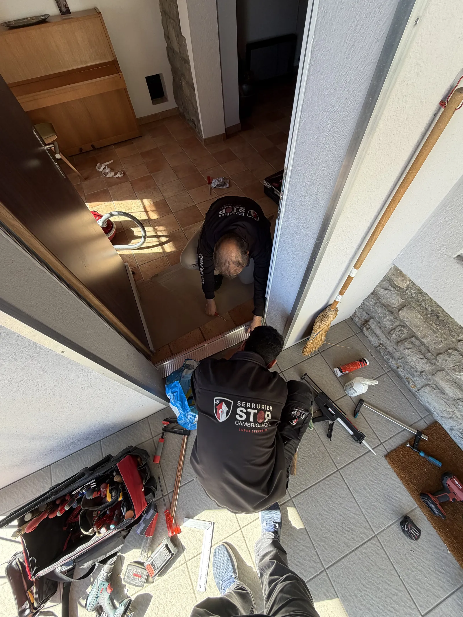 Stop-Cambriolages craftsmen replacing a door threshold in an apartment building